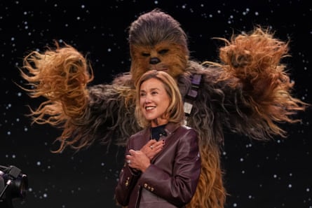 Chewbacca the Wookiee, from the Star Wars saga, rears up behind Lego executive vice-president Julia Goldin, before a backdrop displaying deep space, studded with stars and planets