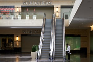 A worker wearing a protective mask disinfects the hand rails on an escalator at NorthPark Center mall in Dallas, Texas, U.S., on Friday, May 1, 2020.
