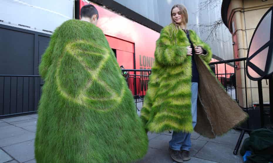 Climate change activists model 'grass' coats during an Extinction Rebellion protest outside a London fashion week event