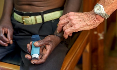 A man holds a blue asthma inhaler in his hand