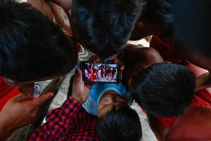 Waiapi children watch a video of a traditional tribal dance on a mobile phone in Manilha, Brazil
