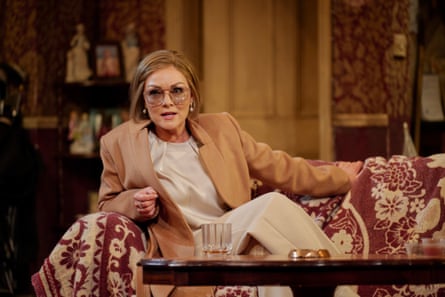 A glamorous looking woman in sunglasses sits on a sofa.