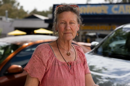 Jacqui, a former art teacher and support person, stands outdoors near parked cars