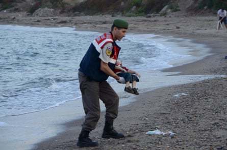 A Turkish gendarmerie carries a young migrant, who drowned in a failed attempt to sail to the Greek island of Kos, in the coastal town of Bodrum, Turkey