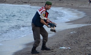 A Turkish police officer carries a young boy, who drowned in a failed attempt to sail to the Greek island of Kos.