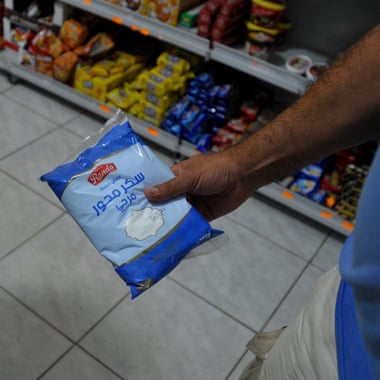 A hand holding a pack of sugar
