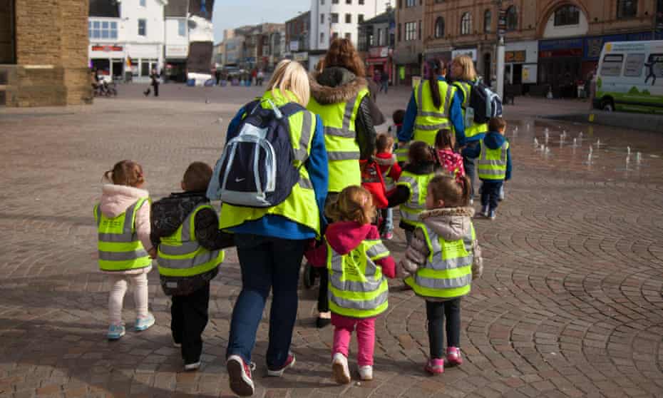 Young children wearing protective fluorescent hi-vis hazard jackets on walk around Blackpool with carers