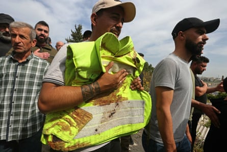 A man carries the blood stained jacket of a first responder