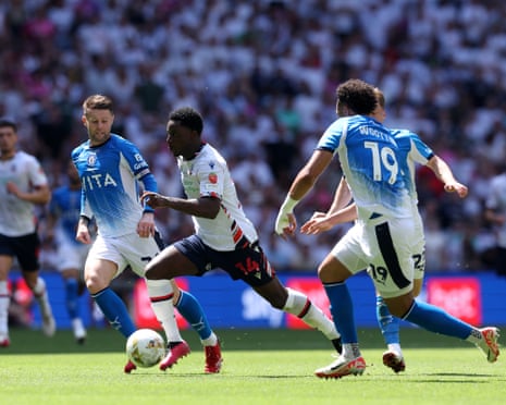 Osei-Tutu runs with the ball while under pressure from Norwood and Wootton,