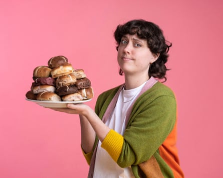 Lucy Knight, with her eyebrow raised, holds a plate piled high with non-traditional hot cross buns