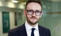 Chris Stark, wearing glasses and a suit, smiling at the camera in a posed photograph