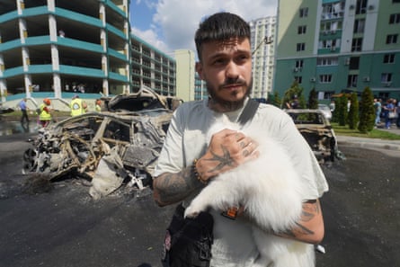 A man comforts his dog outside a bombed residential building