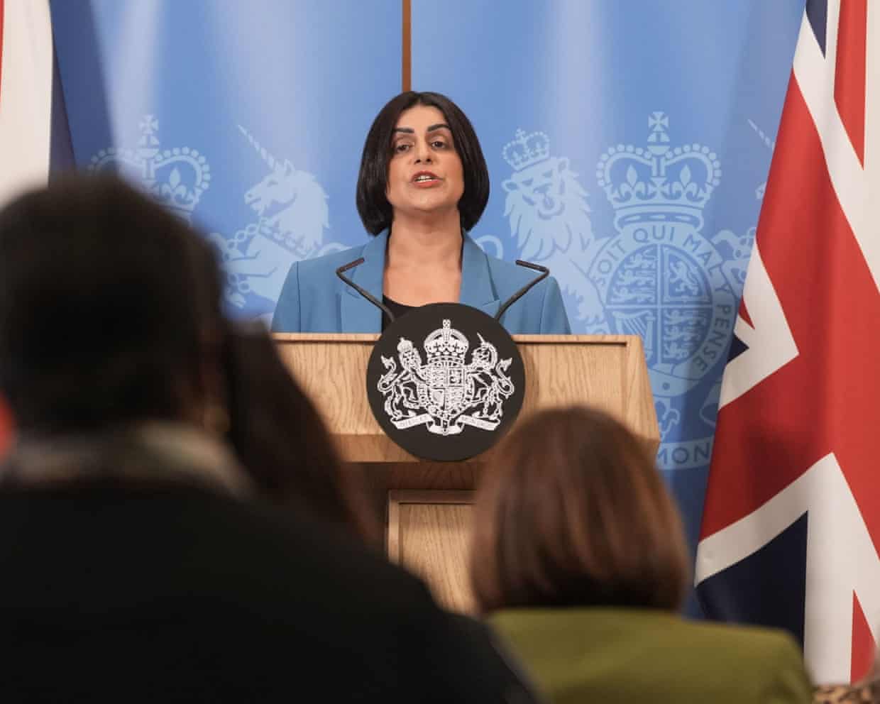 Mahmood stands at a lectern, with a union flag to her left
