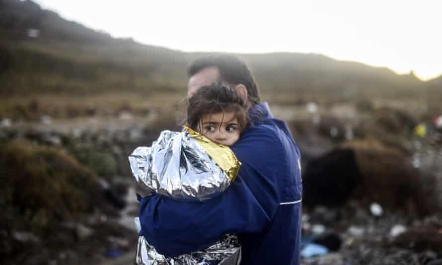 A man holds a young girl after arriving with other refugees at the Greek island of Lesbos