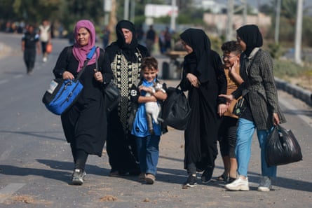 Four women and two children carry their belongings and a pet cat walk along the Salah-al-Din road in Gaza.