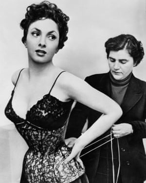 A wardrobe assistant helps Gina Lollobrigida get into her corset in 1954