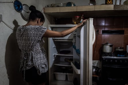 A woman stares into her empty fridge at her house in Petare
