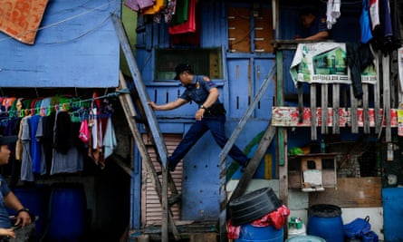 A police officer moves between houses during a police operation against illegal drugs at a slum area in Manila.