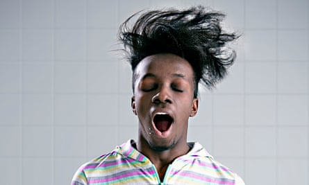 A young man wearing a onesie, yawning