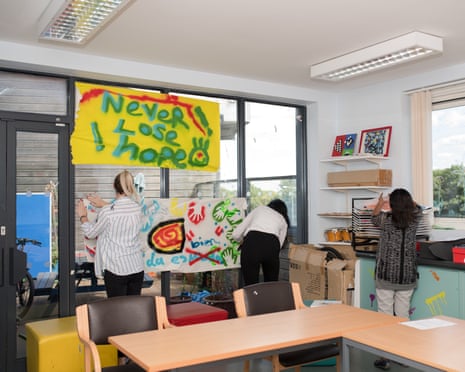Three people hanging banners in a room below one that reads 'never lose hope'