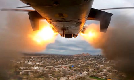 A Ka-52 helicopter, flying over an area in Ukraine with buildings and houses, fires two flaming rockets at an unknown target.  