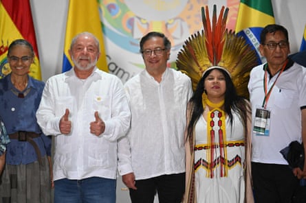 Three men pose with two women, one of whom as a feathered headdress on