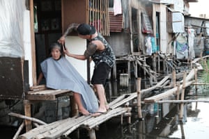 Across the street from the cemetery, there is a row of squatter homes above sewage water. This woman is paralyzed from the waist down, and has not had her haircut in ages.