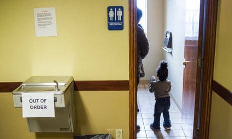 A child walks into the bathroom to wash her hands after passing an out of order water fountain before receiving a free lead test in February in Flint.