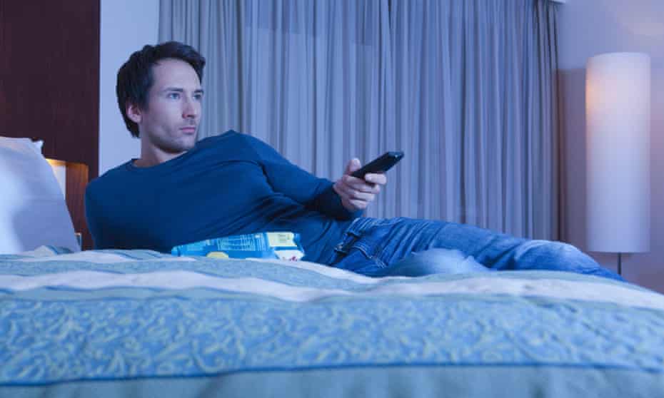 A man on a bed watching TV