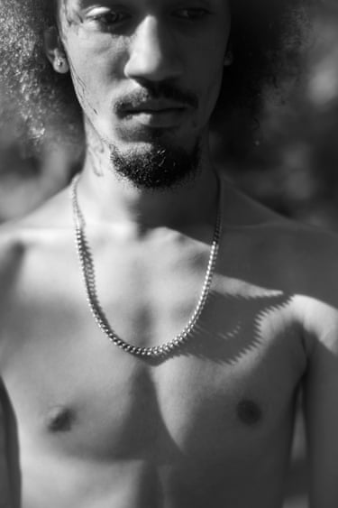 A close-up of a young man with an eye shaped shadow on his upper torso