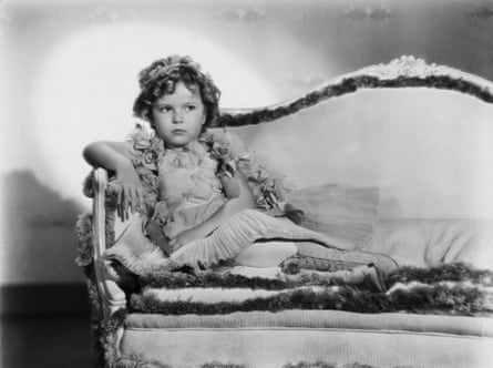 Black and white photograph of Shirley Temple sitting on an ornate sofa, taken c1935