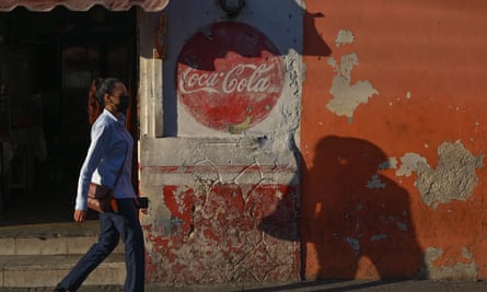 Woman walks past Coca-Cola advert in Merida, Mexico, February 2022.