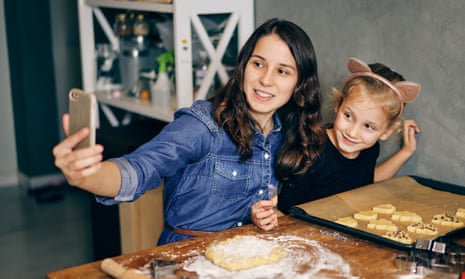 Mother and daughter making video call from smartphone while baking at home.