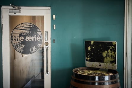 A moss-covered computer monitor sits on a barrel beside the Aerie’s entrance door