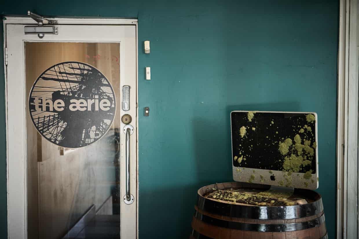 A moss-covered computer monitor sits on a barrel beside the Aerie’s entrance door