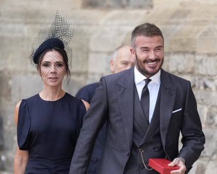 Beckhams dressed smartly outside, David holding red box