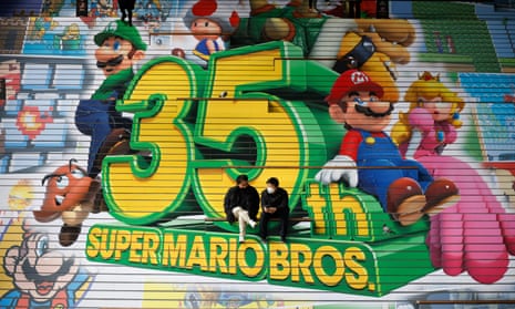 Men wearing face masks talk in front of an advertisement promoting the 35th anniversary of Super Mario Bros at a shopping mall amid the coronavirus disease (COVID-19) outbreak in Seoul, South Korea