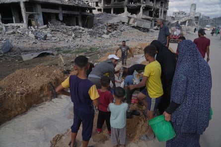 Palestinians collect water from a broken pipe in Gaza City