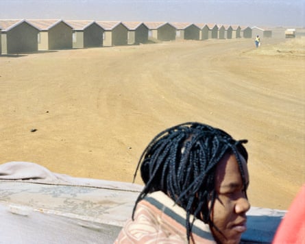 Small new houses on barren land with head and shoulders of woman in foreground