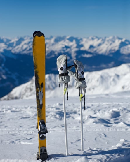 Ski dan tongkat ski dengan sarung tangan di ujungnya tertancap tegak di dalam salju La Plagne.