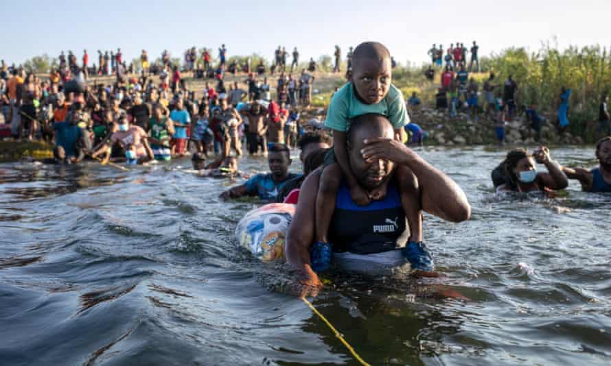 l'enfant monte sur les épaules de l'homme alors que l'homme patauge dans l'eau et se couvre les yeux