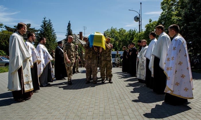 Servicemen carry a coffin covered with the national flag between two rows of priests during the funeral  in Uzhhorod, western Ukraine, of Ukrainian soldiers Oleksandr Serousov and Robert Madyar.