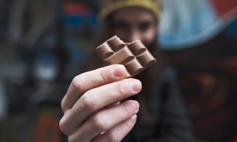 close up on a woman's hands holding a bitten piece of chocolate barPX6TF7 close up on a woman's hands holding a bitten piece of chocolate bar