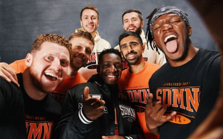 Seven sidemen posing for the camera in black T-shirts and orange ‘Sidemen’ logos