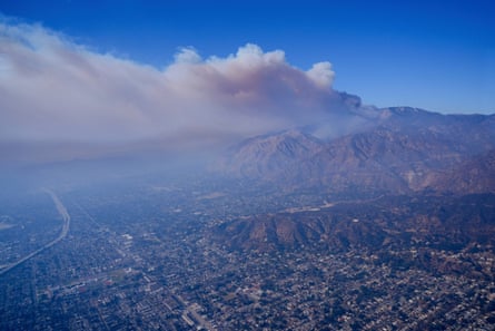 A plume of smoke from a wildfire forms over a city