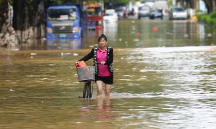 A woman walks her bicycle through a street flooded by heavy rains from Typhoon Sanba in Maoming, southern Guangdong province.