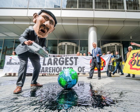 A campaigner wearing a Rishi Sunak mask pouring oil over the world as part of an Extinction Rebellion protest outside Shell’s AGM.