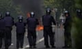 Garda public order unit in protective gear stand in a line facing a small fire