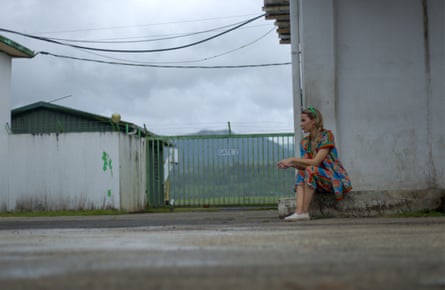 Victoria Baker-Harber sitting on a kerb outside a white building. A gate to the airfield is behind