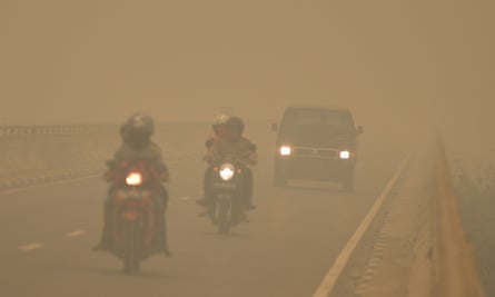 Commuters drive through thick haze in Tumbang Nusa, Central Kalimantan, on October 25, 2015. Indonesia has put warships on standby to evacuate people affected by acrid haze.